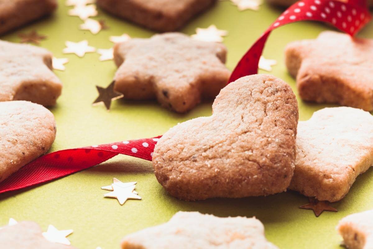 Christmas cookies in heart and star shapes on a counter with red ribbon and decorative stars