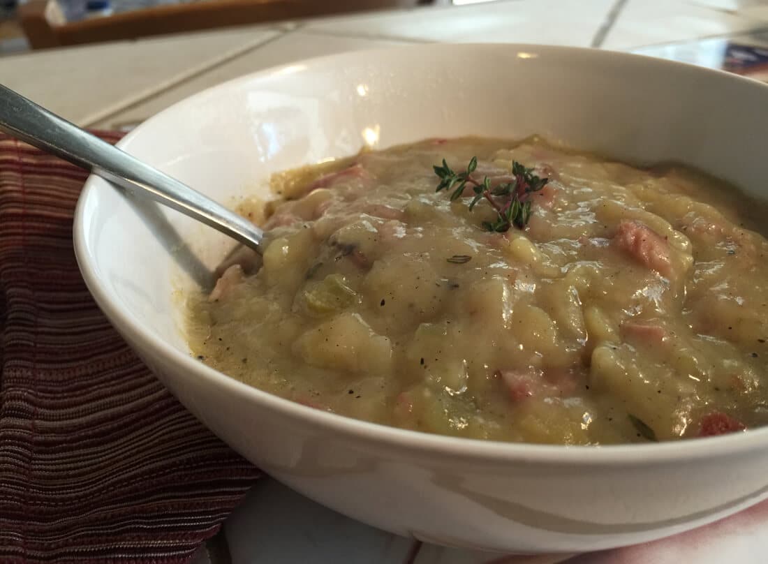 creamy ham and potato soup in a bowl with a spoon on a table