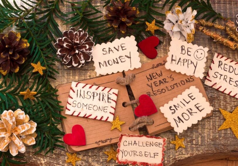 New Years resolutions written on decorative cards on a table decorated with pine cones and felt hearts