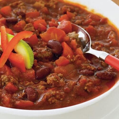 white bowl full of chili garnished with avocado