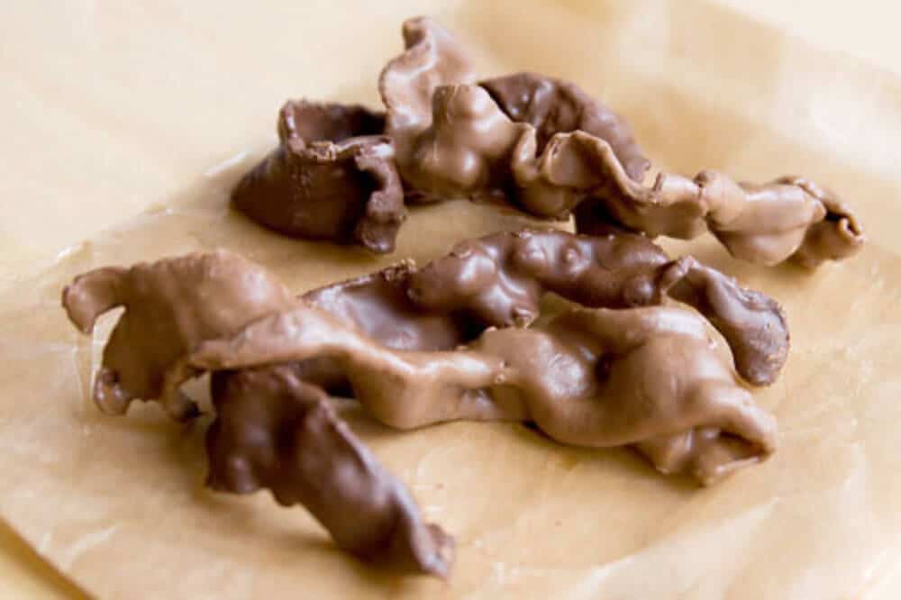 chocolate covered bacon on a wooden cutting board