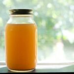 jar of crockpot chicken stock on a table by a window
