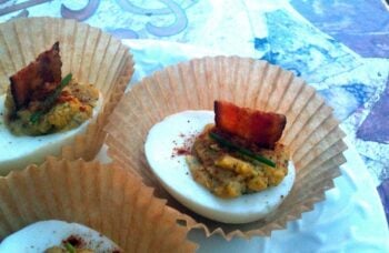 deviled eggs with bacon and dill in a cupcake wrapper on a table