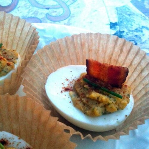 deviled eggs with bacon and dill in a cupcake wrapper on a table