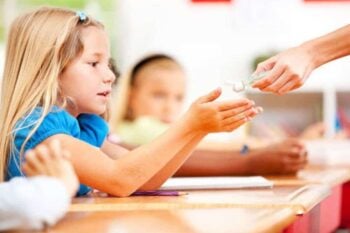 child holding out hands to receive hand sanitizer