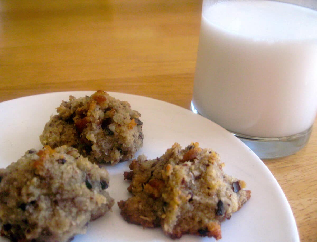 Old fashioned cookies on a white plate with a glass of milk next to it