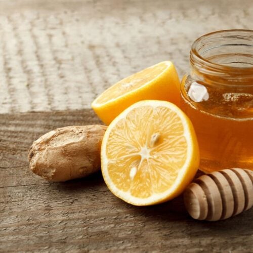lemon, ginger and a glass jar of honey on a wooden table