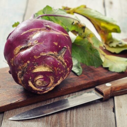 purple kohlrabi on a wooden cutting board with a knife