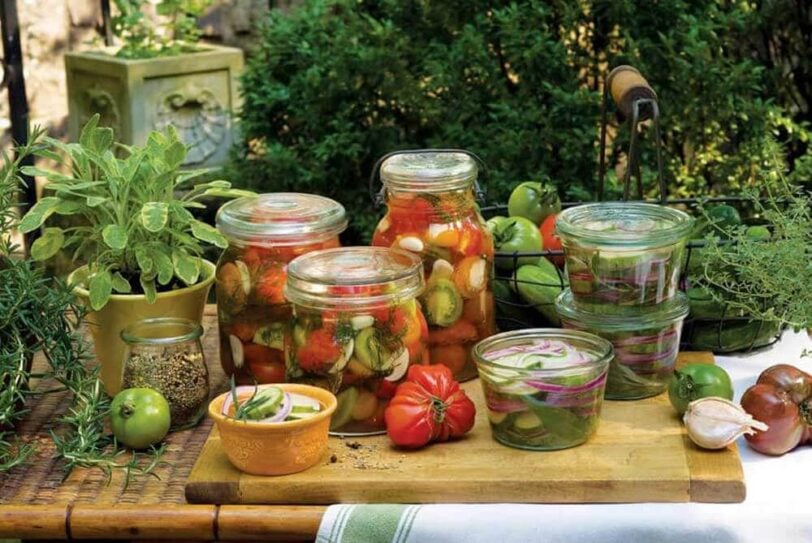 canning jars full of pickles on a wooden table outdoors.