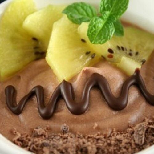 raw vegan chocolate mousse with kiwi garnish in a white dish