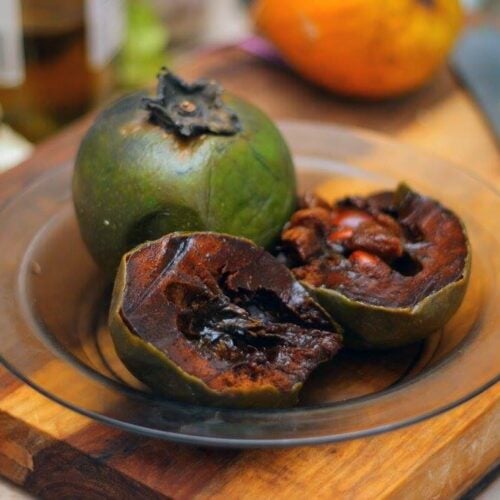 sapote sliced open on a glass plate